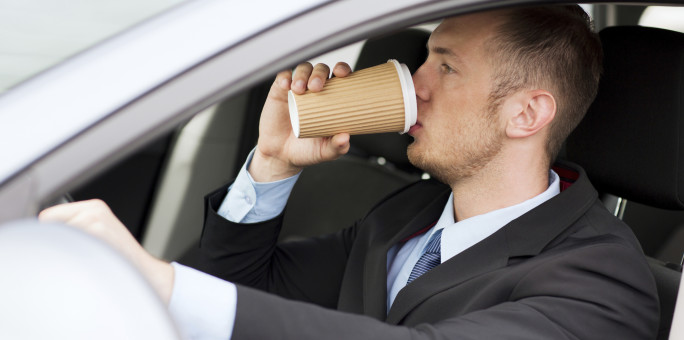 man drinking coffee while driving the car